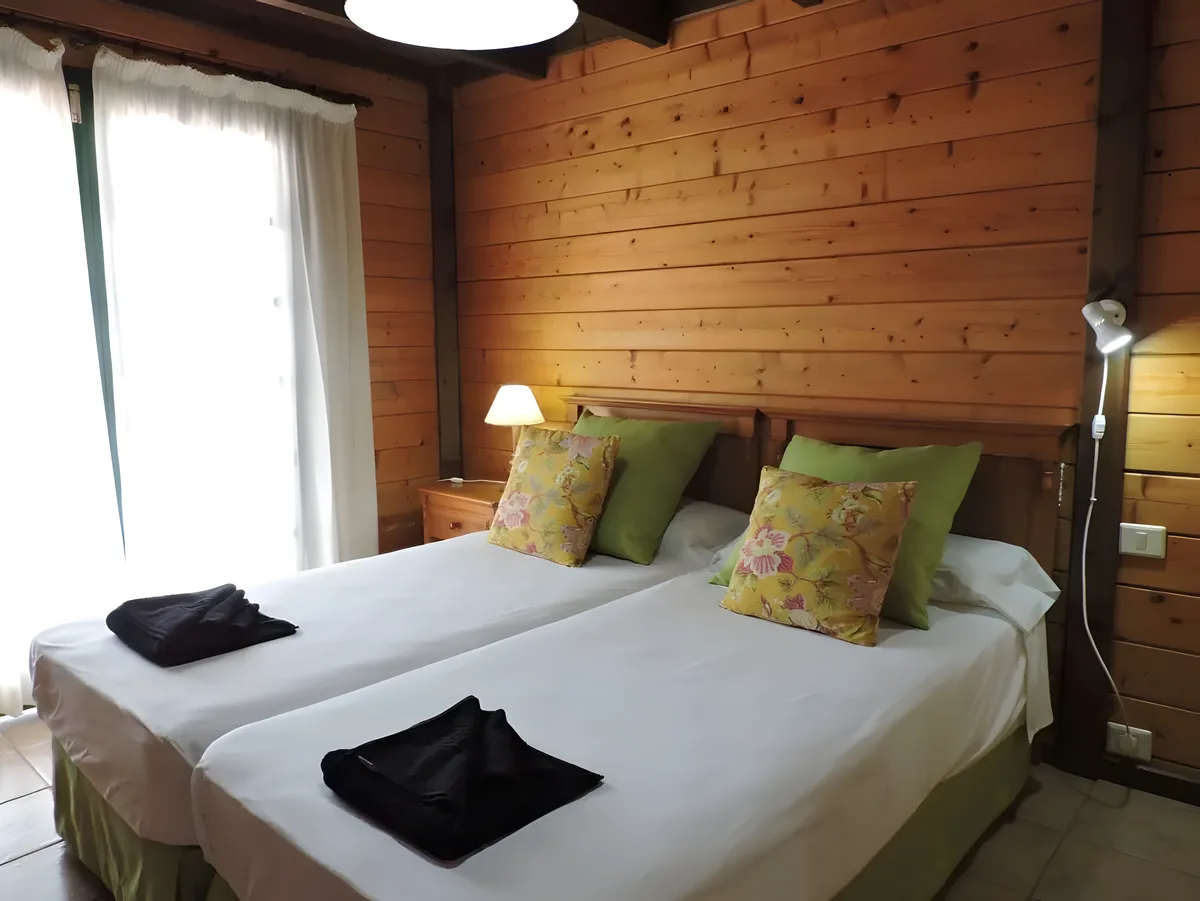 Dormitorio con paredes de madera y cojines verdes